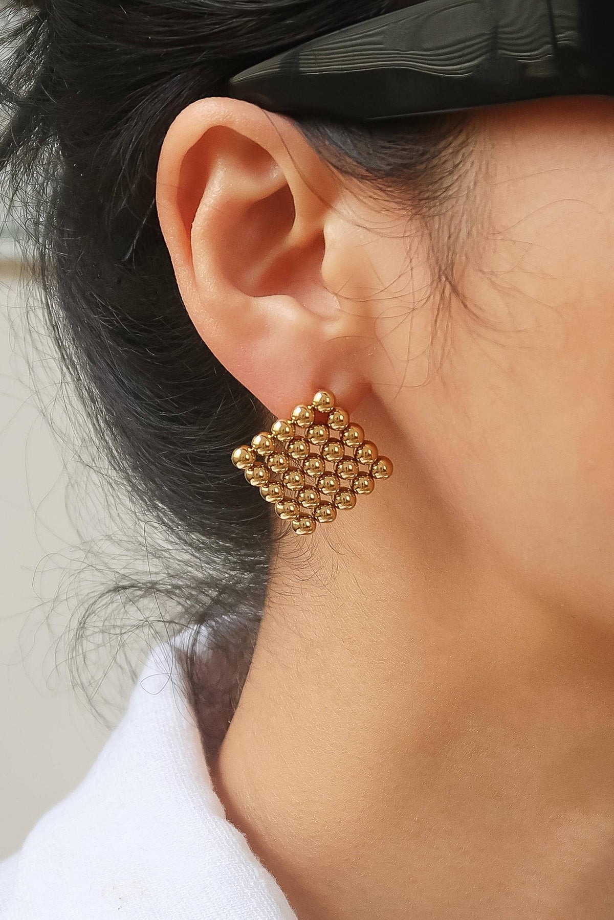 Gold earring worn by a person with a neutral background