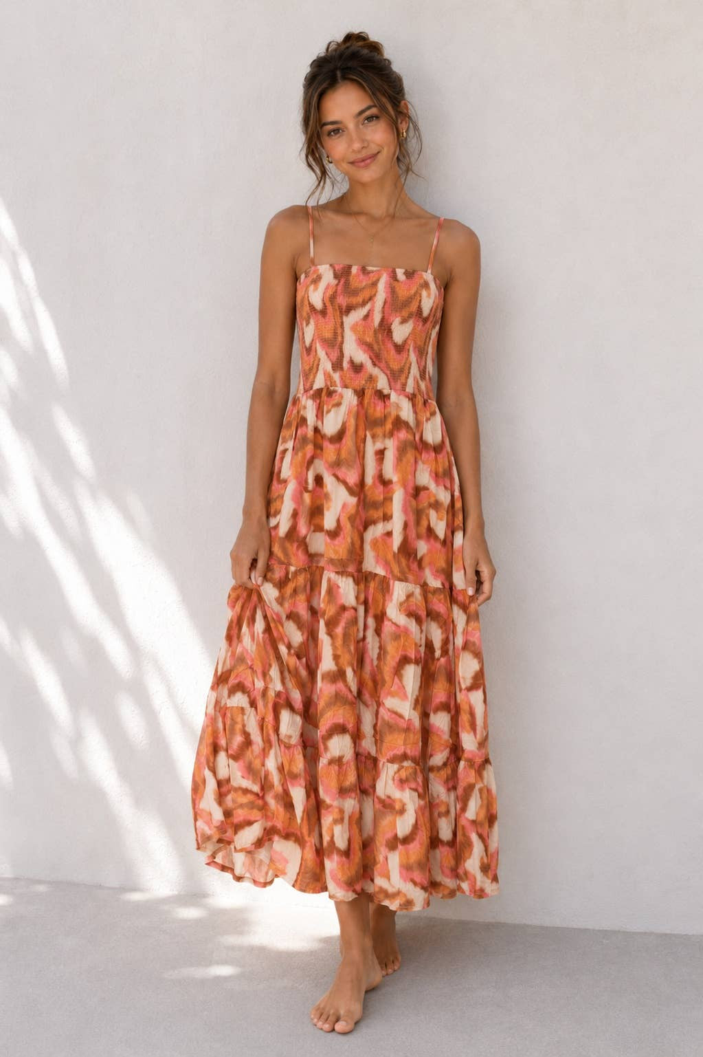 Woman wearing an orange patterned dress against a white background
