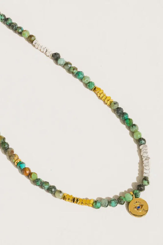 Necklace with green, yellow, and white beads on a light gray background