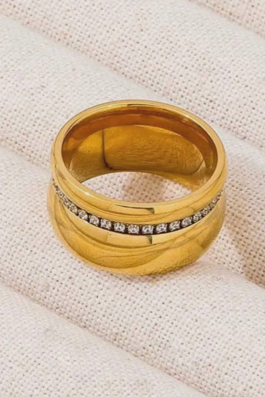 Gold ring with embedded stones on a textured beige fabric background