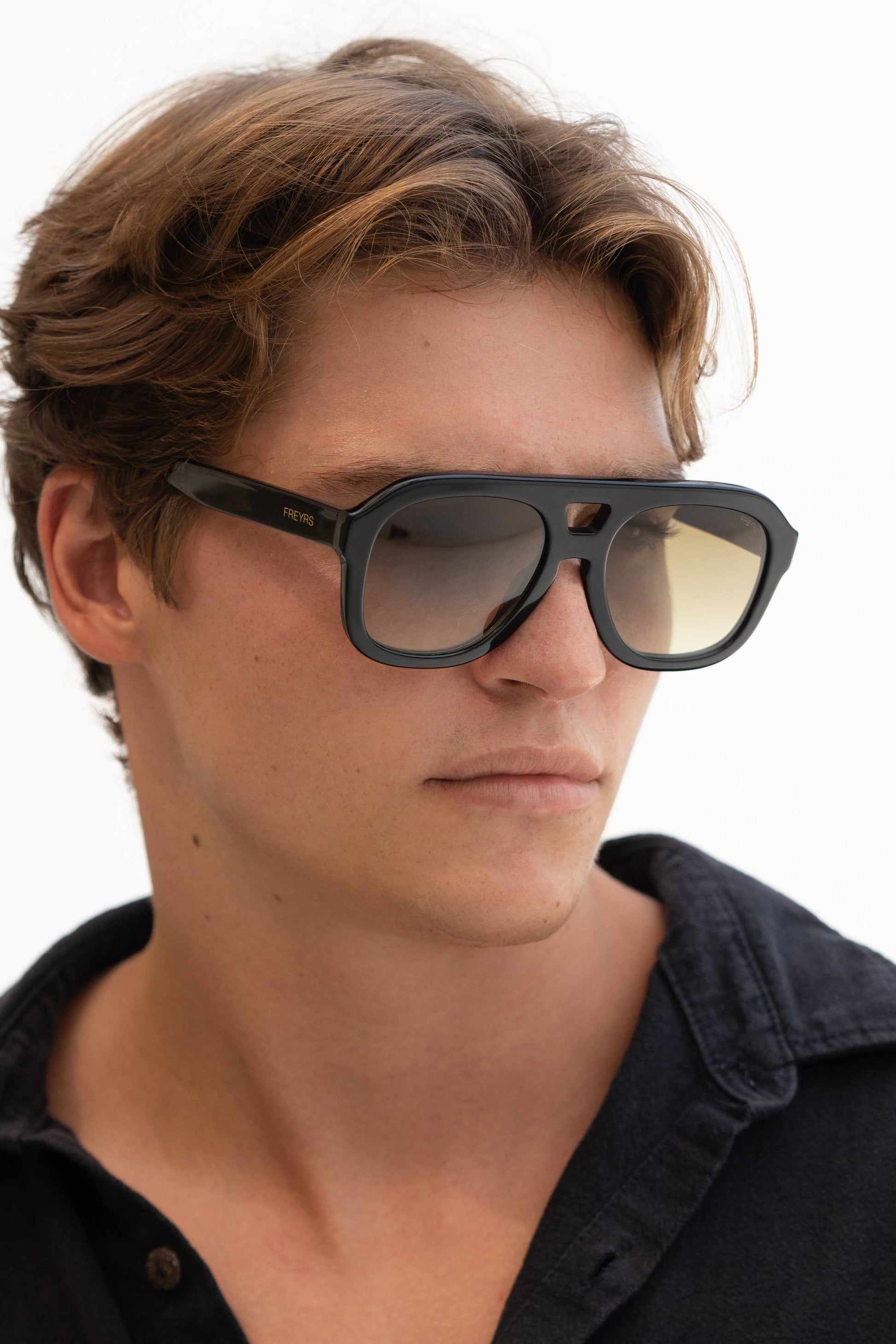 Person wearing black sunglasses with a neutral background