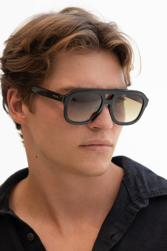 Person wearing black sunglasses with a neutral background