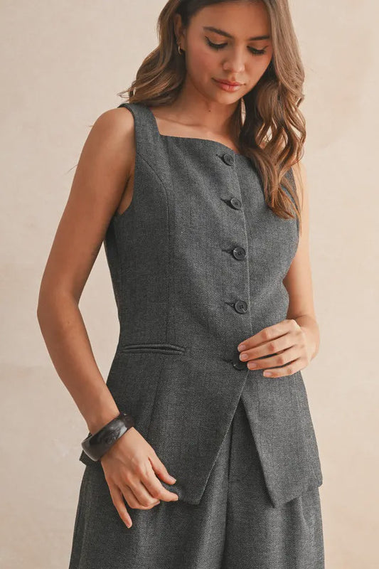 Woman wearing a gray sleeveless dress with buttons on a beige background