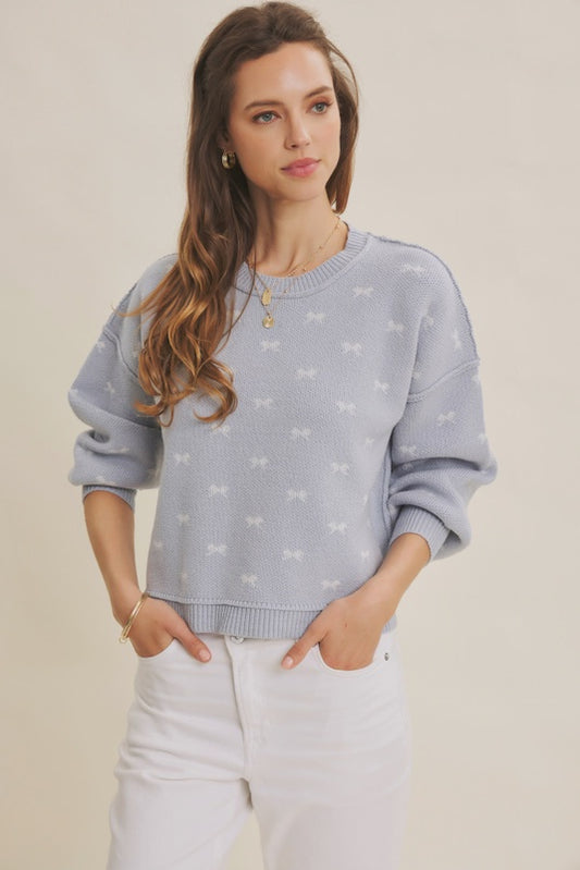 Woman wearing a light blue sweater with bow patterns on a beige background