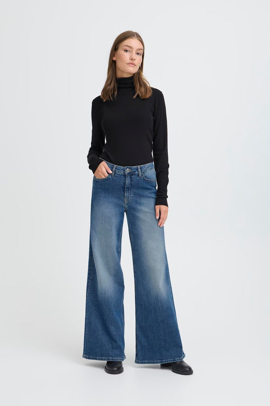 Woman wearing a black turtleneck and blue jeans on a white background