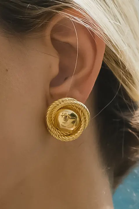 Close-up of a person wearing a gold hoop earring with a blurred background