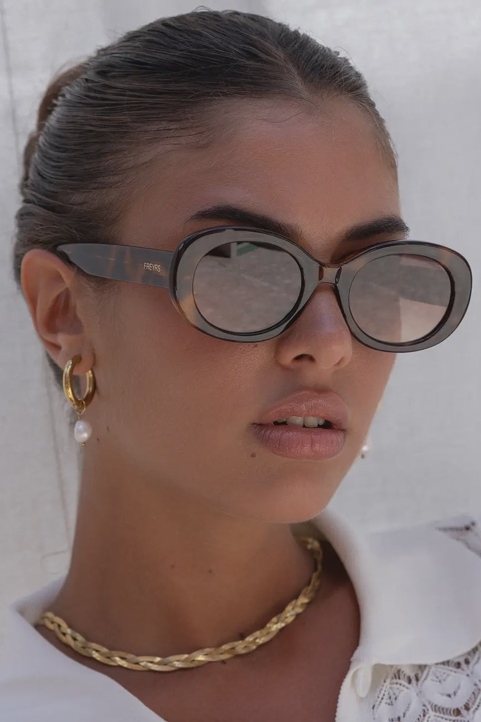 Woman wearing large sunglasses with a neutral background