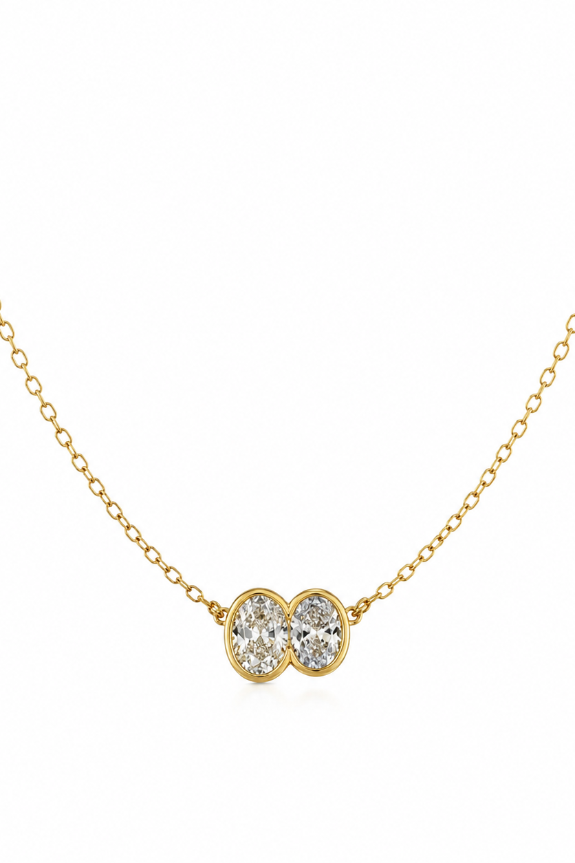 Gold necklace with a double heart-shaped diamond pendant on a white background