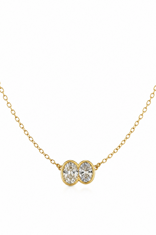 Gold necklace with a double heart-shaped diamond pendant on a white background