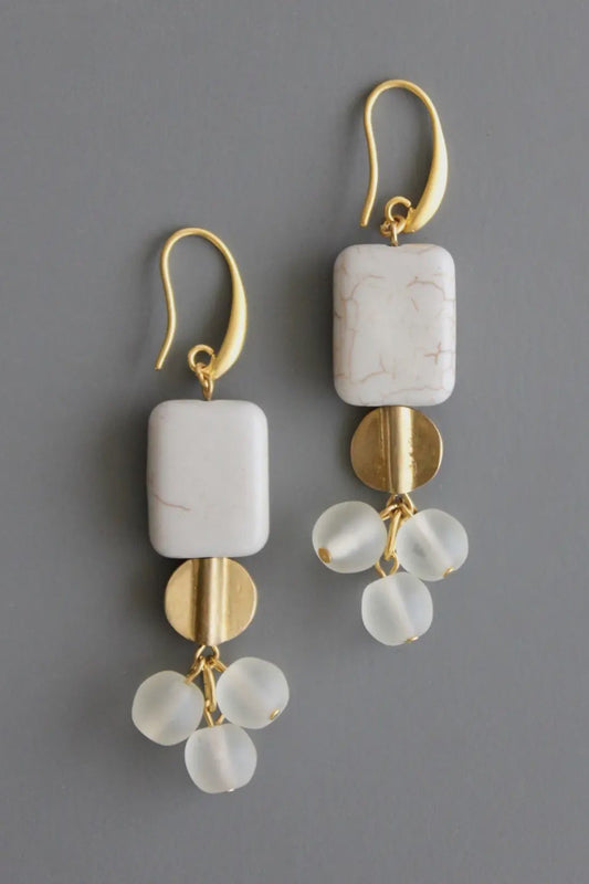 Gold and white stone earrings on a gray background