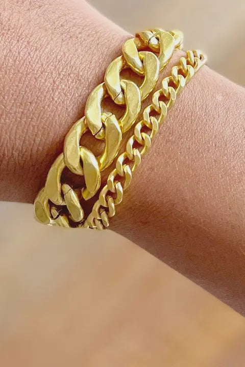 Gold chain bracelet on a wrist with a blurred background