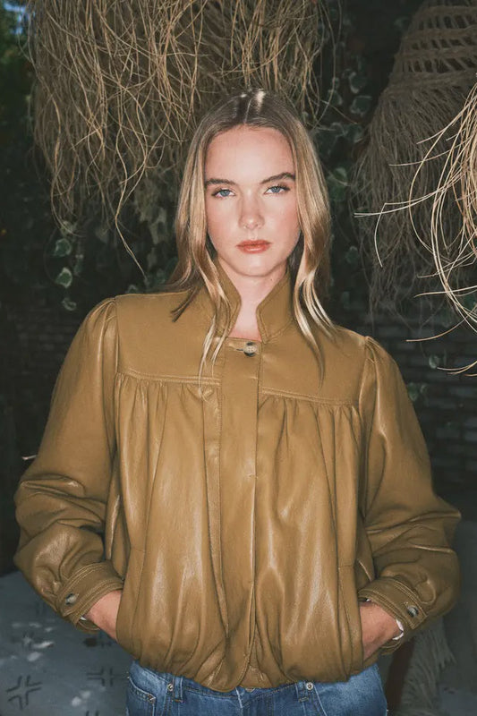 Person wearing a brown leather jacket with a dark background