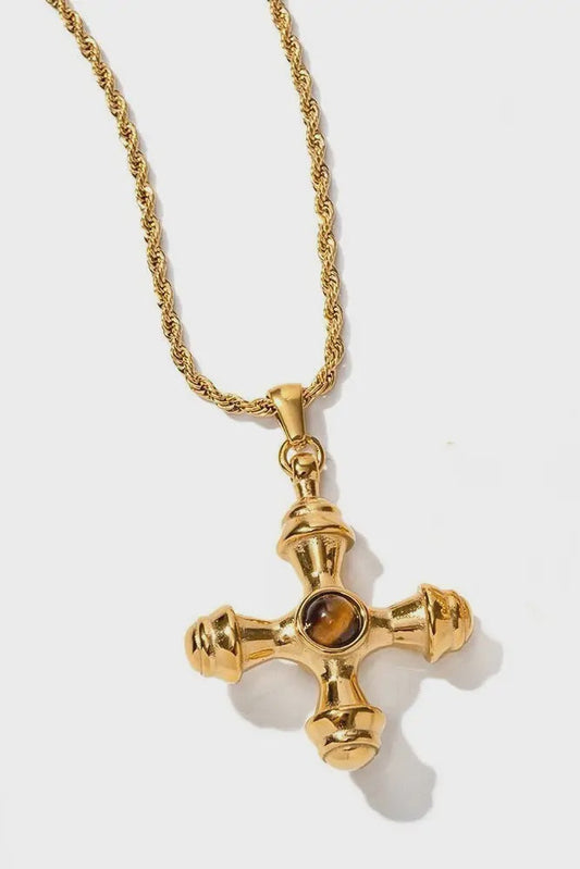 Gold cross necklace with a central gemstone on a white background