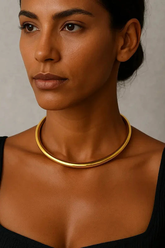 Woman wearing a gold necklace against a neutral background