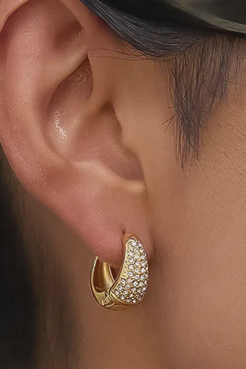 Gold hoop earring with clear stones worn by a person