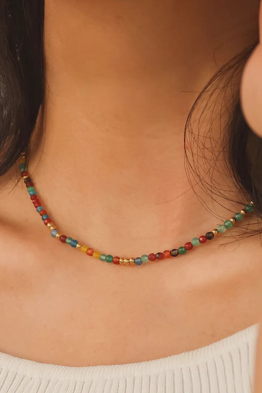 Close-up of a colorful beaded necklace on a person wearing a white sweater.