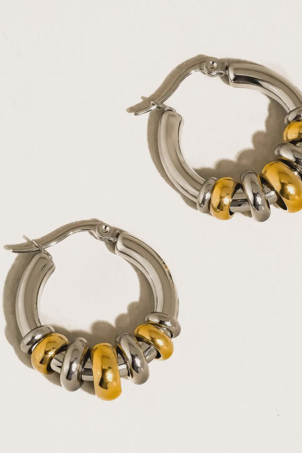 Silver hoop earrings with yellow accents on a light gray background