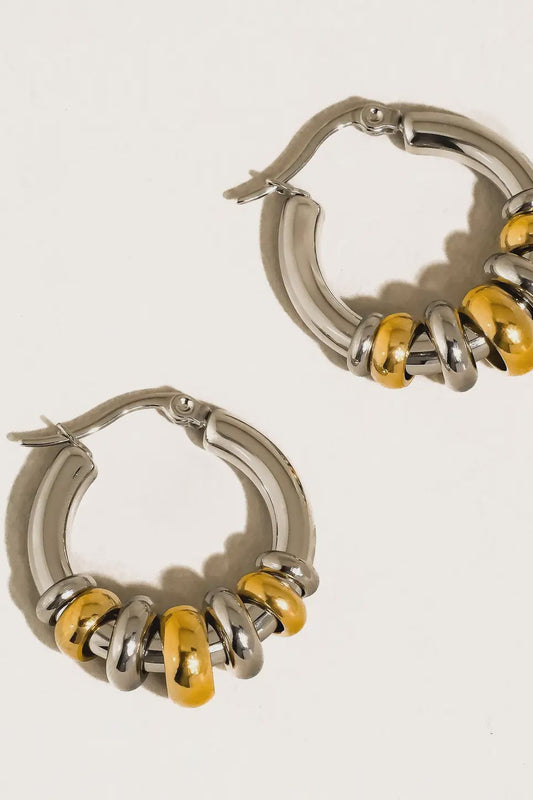 Silver hoop earrings with yellow accents on a light gray background