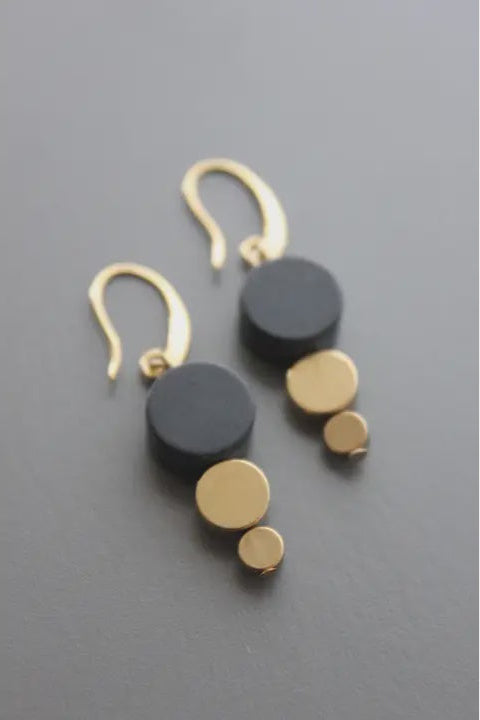 Gold and black earrings on a gray background