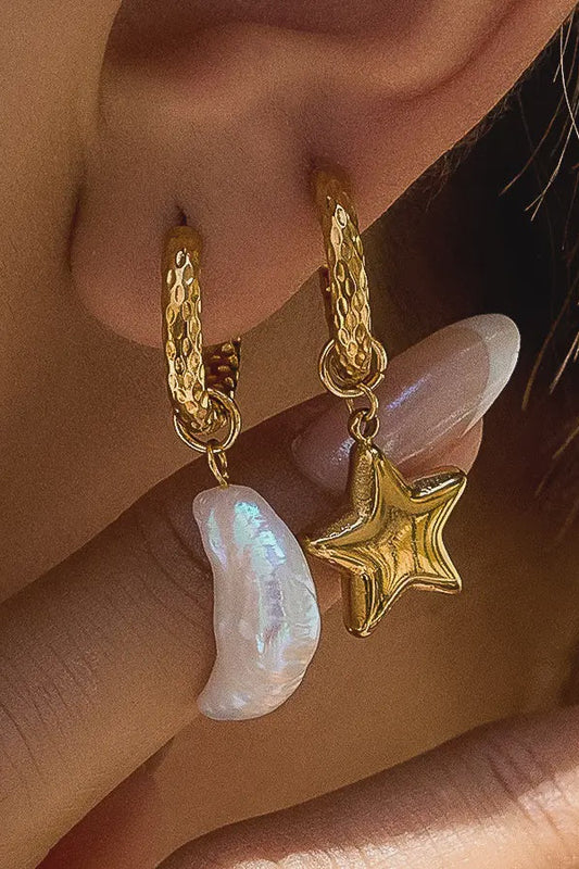Gold hoop earrings with star and pearl charm worn by a person.