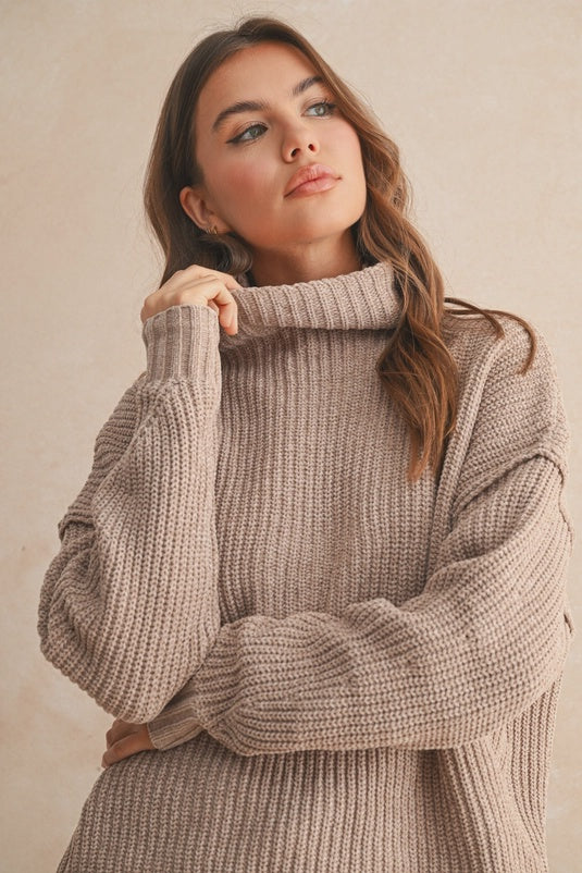 Woman wearing a beige knitted sweater against a plain background