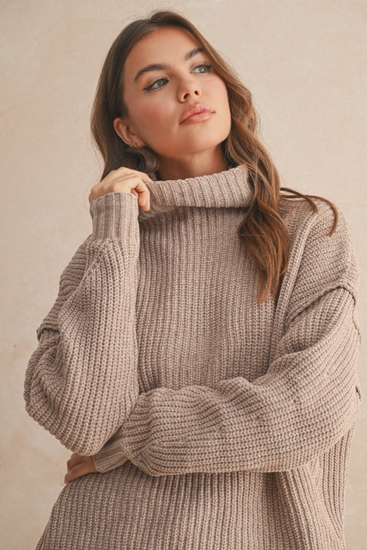 Woman wearing a beige knitted sweater against a plain background