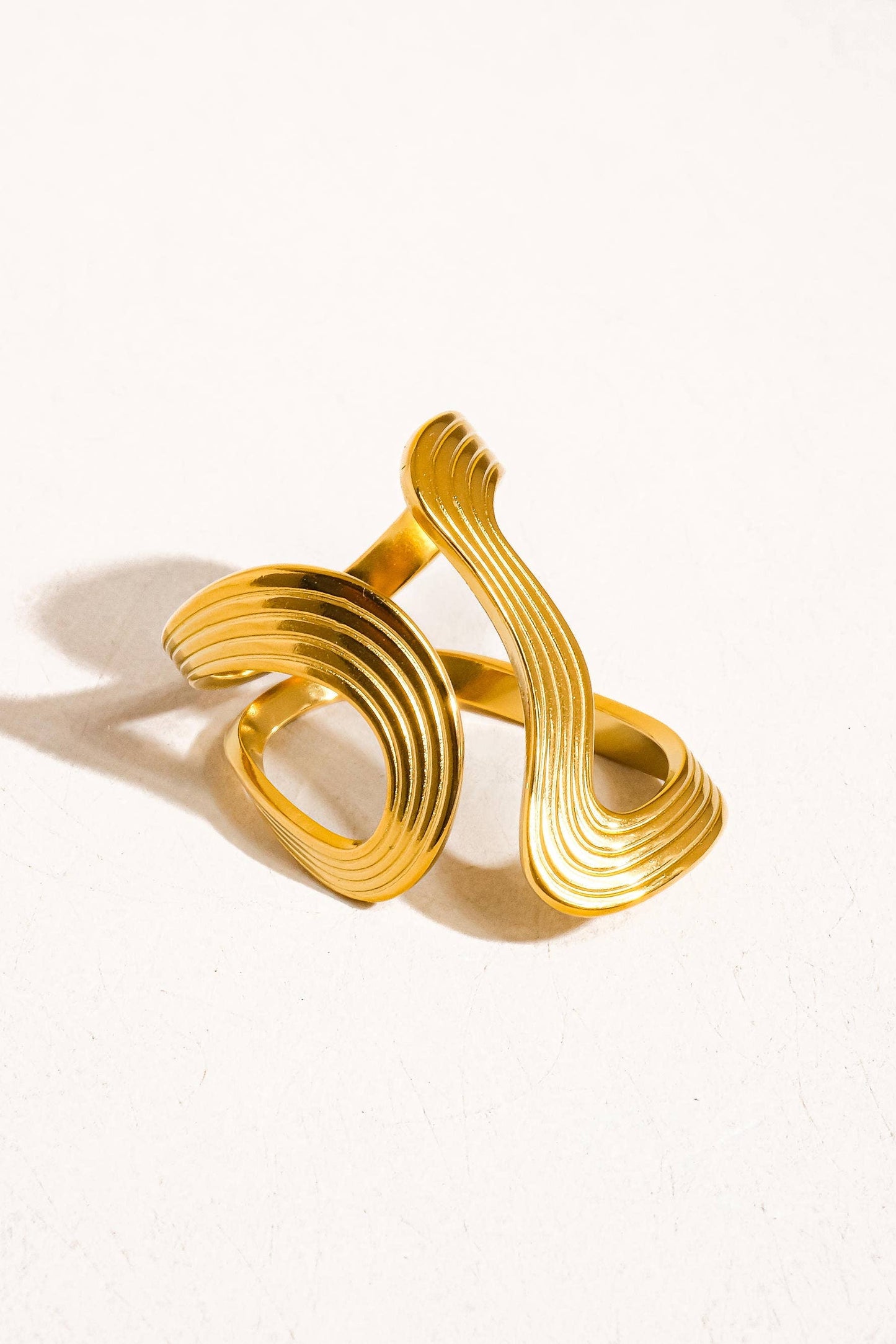 Gold bracelet with wavy design on a white background
