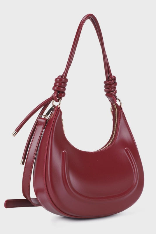 Red handbag with a strap on a light gray background