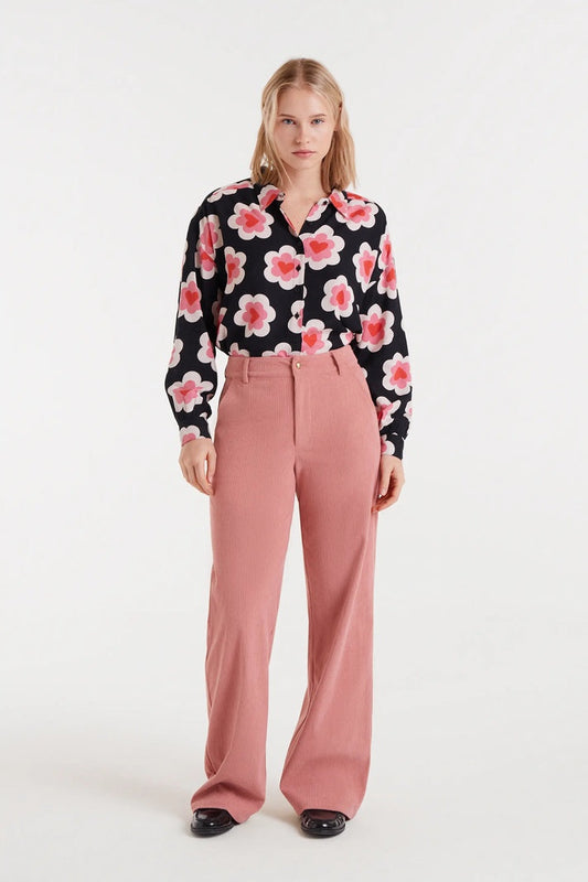 Woman wearing a floral blouse and pink pants on a white background