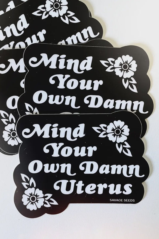 Stack of 'Mind Your Own Damn' stickers with floral designs on a white background