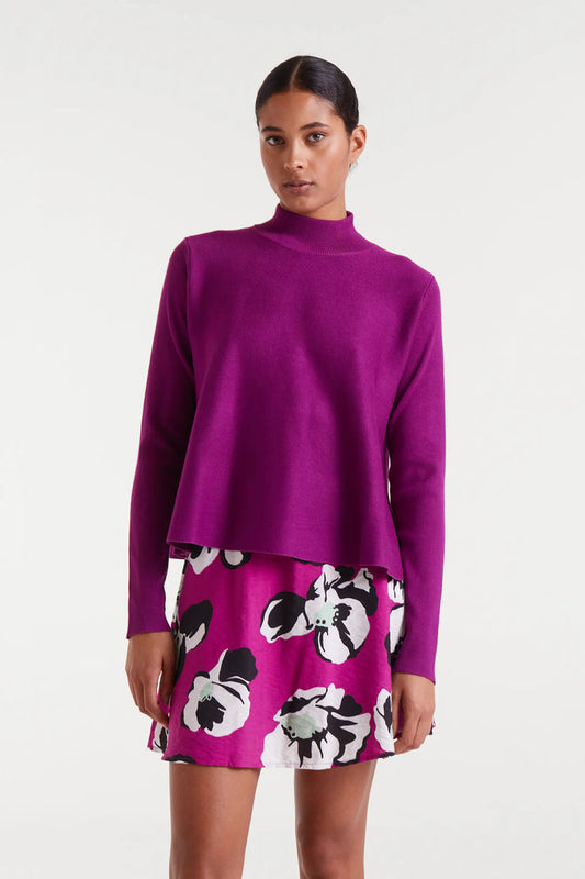 Woman wearing a purple sweater and floral skirt on a white background