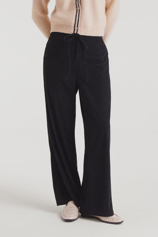 Person wearing black wide-leg pants on a plain background