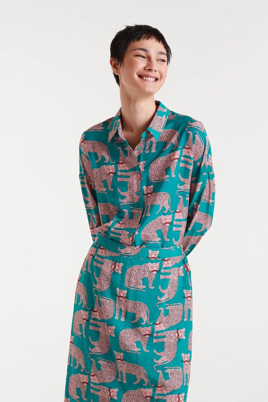 Person wearing a teal dress with pink animal pattern on a white background