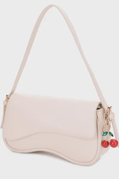 Beige handbag with cherry charm on a light gray background