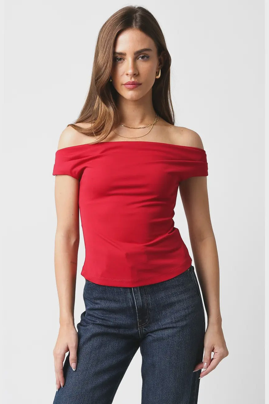 Woman wearing a red off-shoulder top and blue jeans on a white background