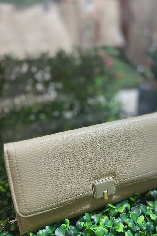 Beige wallet on green grass with blurred background