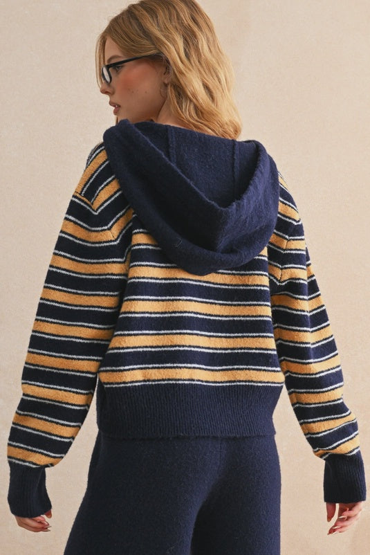 Person wearing a striped sweater with a hood on a beige background