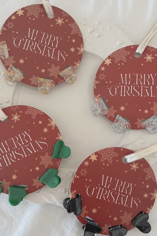 Four round red 'Merry Christmas' ornaments with various decorative clips on a white background.