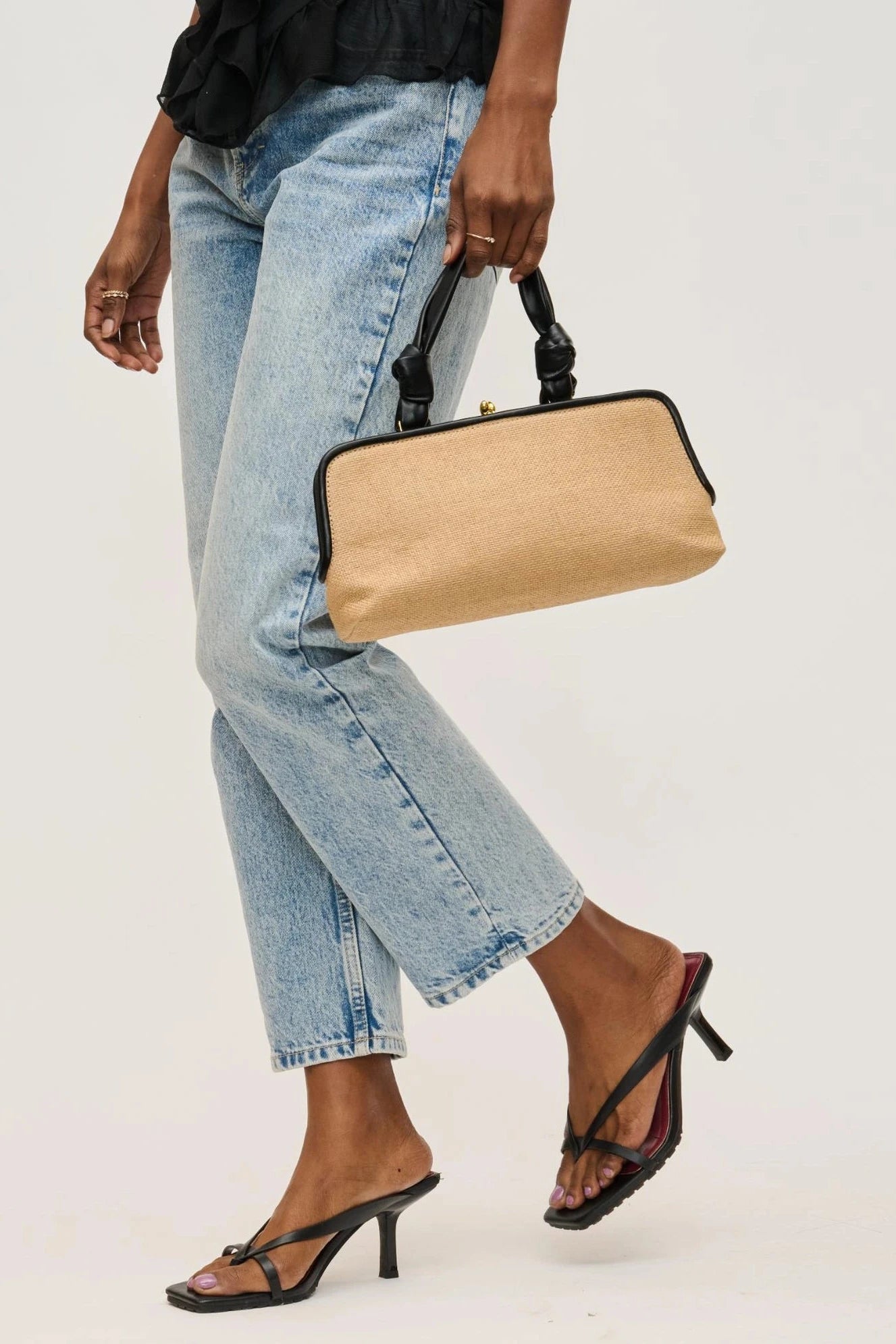 Person holding a beige clutch bag with a plain background