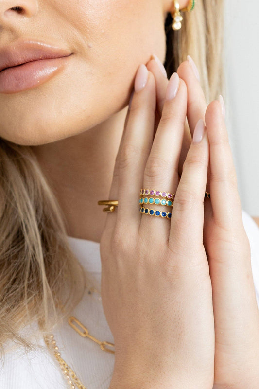 Close-up of a woman's face with gold jewelry on her fingers and neck.