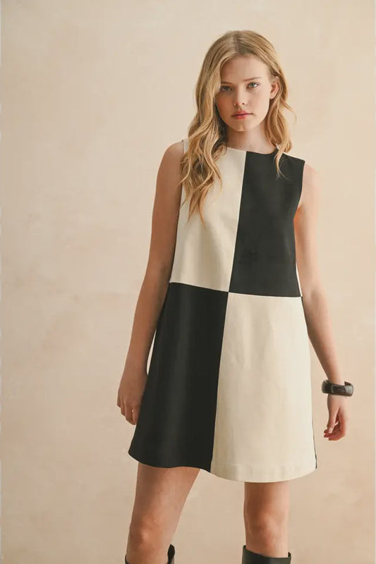 Woman wearing a black and white dress against a beige background