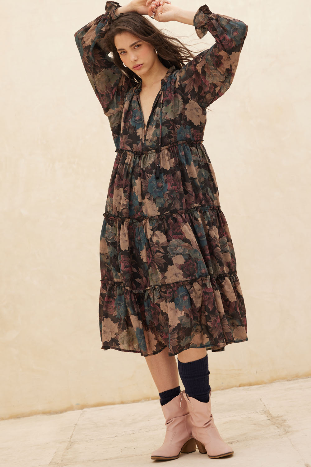 Woman wearing a floral dress and pink boots against a beige background