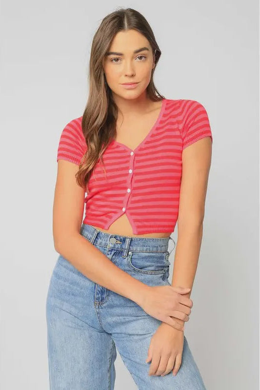 Woman wearing a pink striped crop top and blue jeans on a gray background
