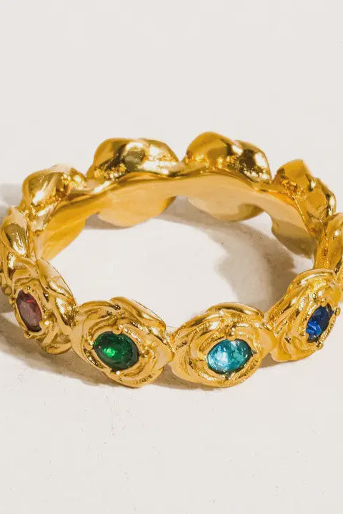 Gold ring with embedded gemstones on a light background