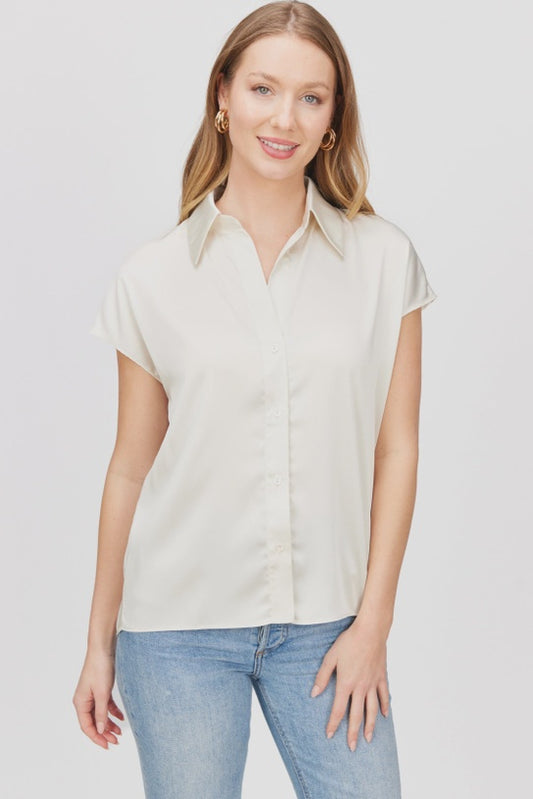 Woman wearing a light-colored shirt and blue jeans against a plain background
