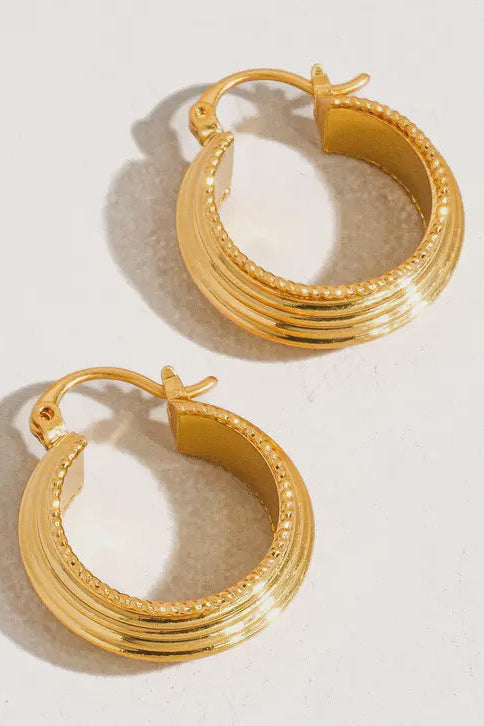 Pair of gold hoop earrings on a light background