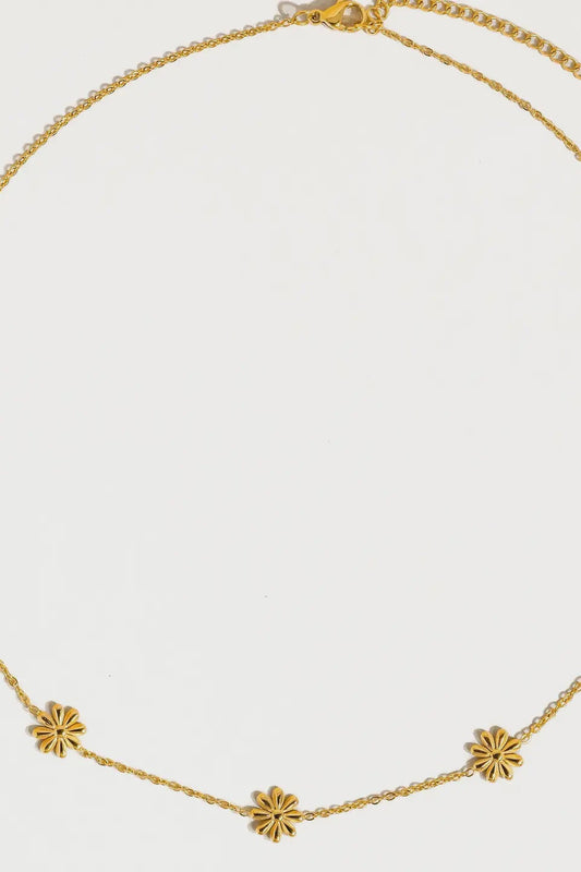 Gold necklace with floral pendants on a light gray background