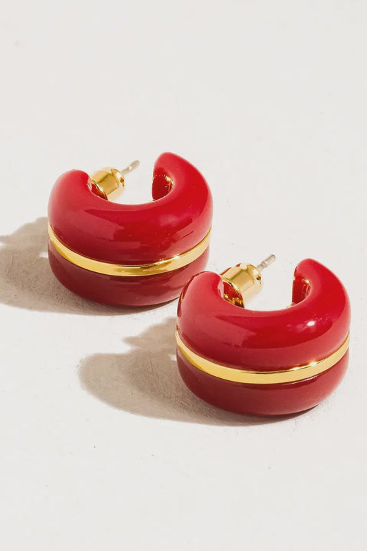 Red hoop earrings with gold accents on a light beige background