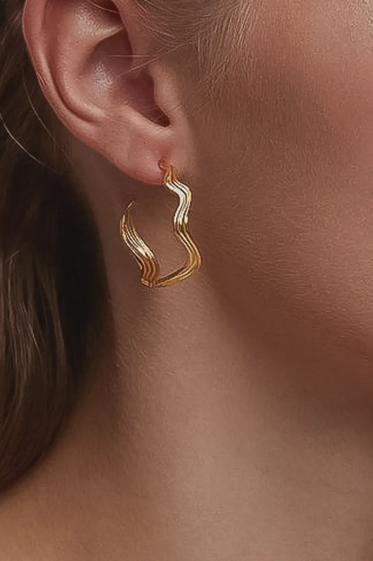 Gold hoop earrings worn by a person with brown hair.