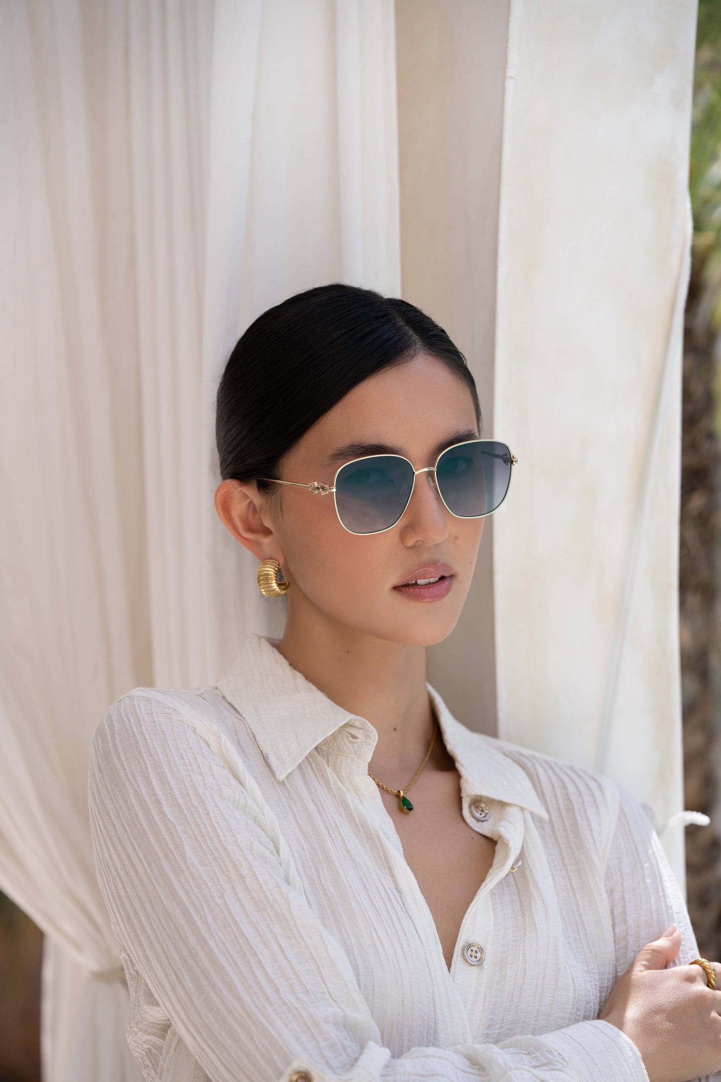 Woman wearing sunglasses and a white blouse with a neutral background
